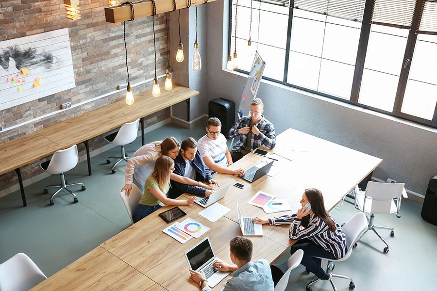 About Us - Team Working in Modern Office with Large Windows on Wooden Desk